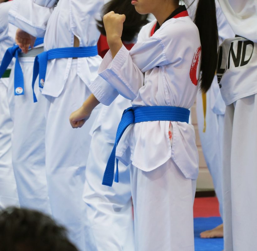 Group of Taekwondo students wearing white uniforms standing practice in class closeup background