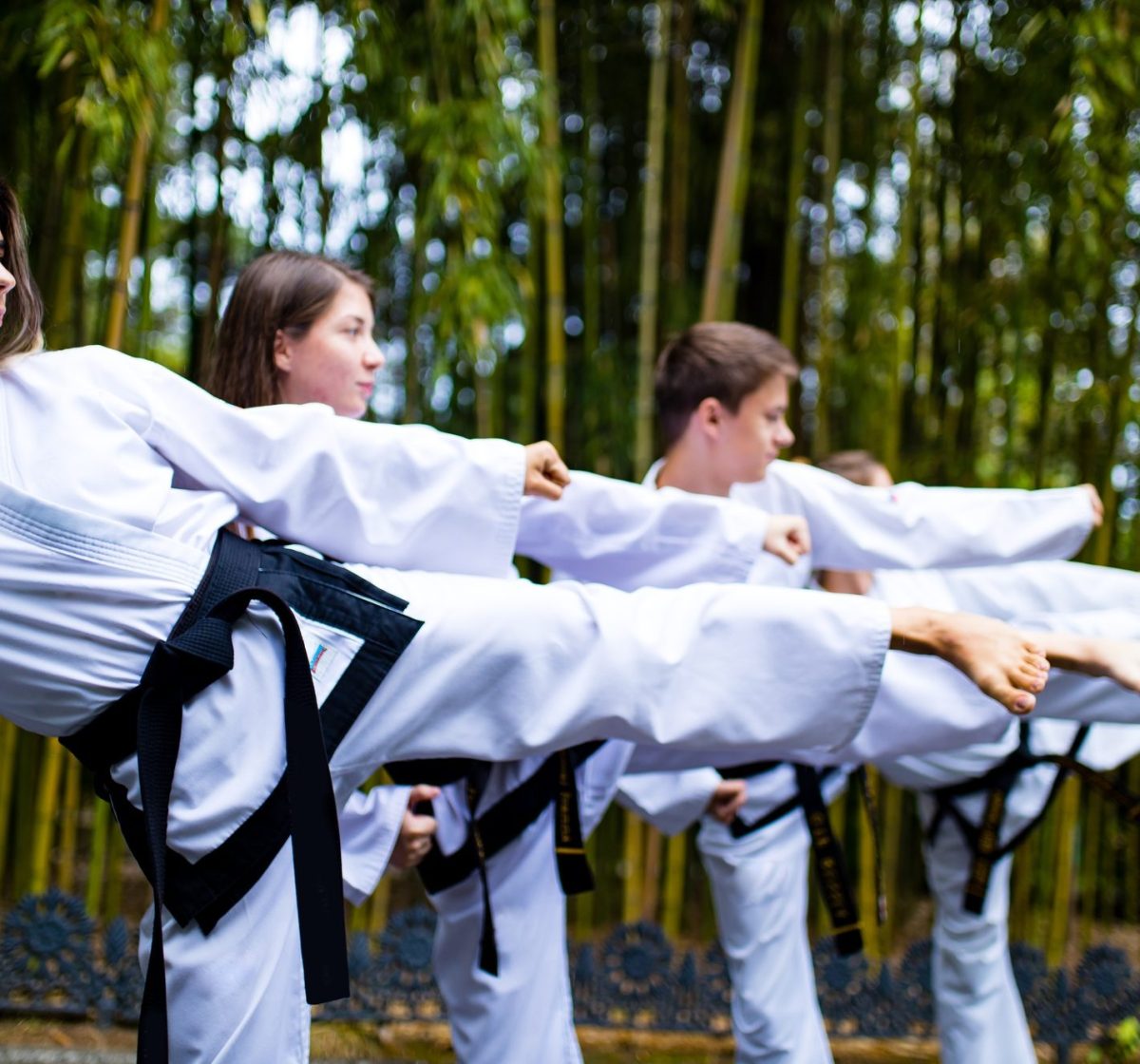 people high kicks during training of taekwondo outdoors bamboo background.