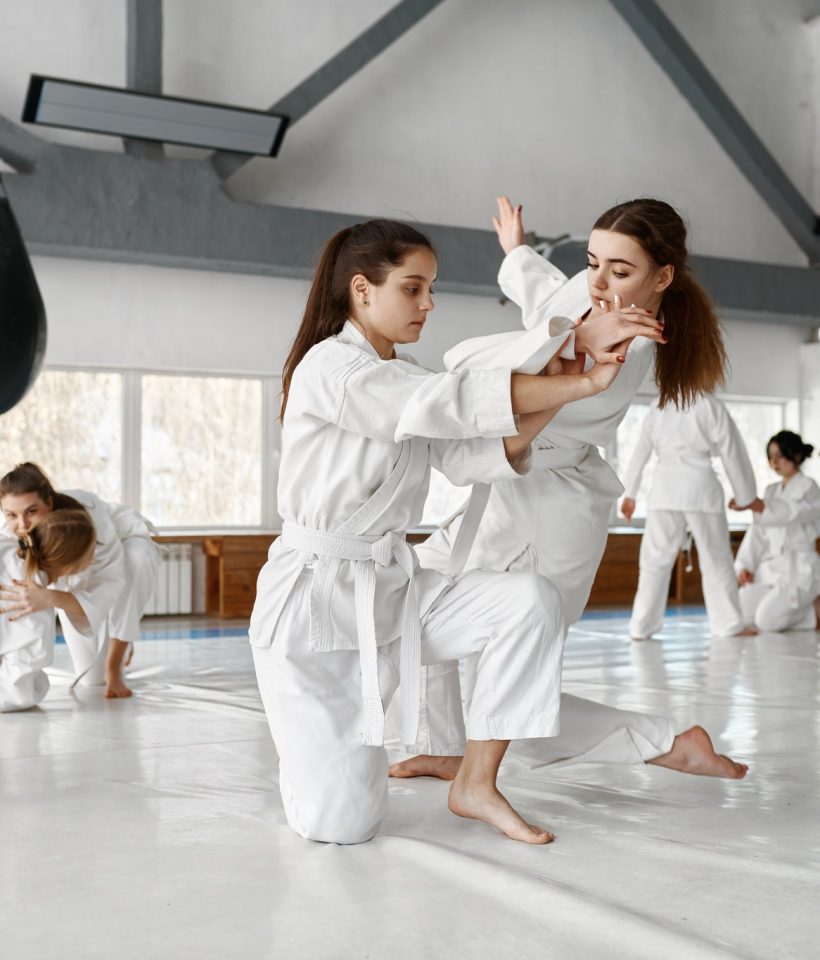 Teenage girls fighting at aikido training in martial arts school